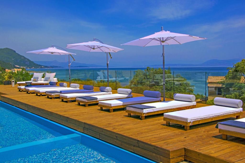 a row of lounge chairs with umbrellas on a pool at Ionian Eye Design Studios & Spa in Mesongi