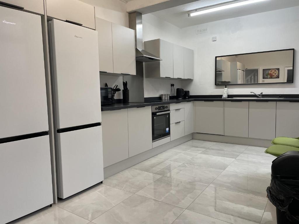 a white kitchen with white cabinets and appliances at Elm, Large 5 Bedrooms, Sleeps 10 With Parking in Birmingham