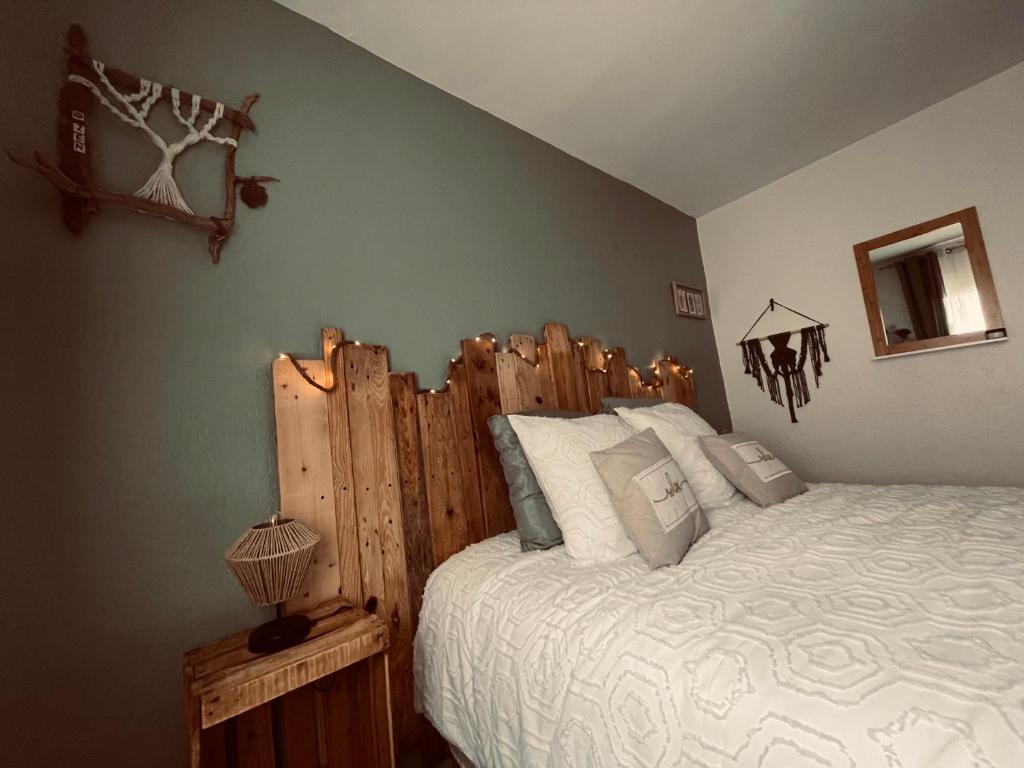 Schlafzimmer mit einem großen Bett mit einem Kopfteil aus Holz in der Unterkunft Maison « l’effet-mère »en rez de chaussée  in Aigues-Mortes