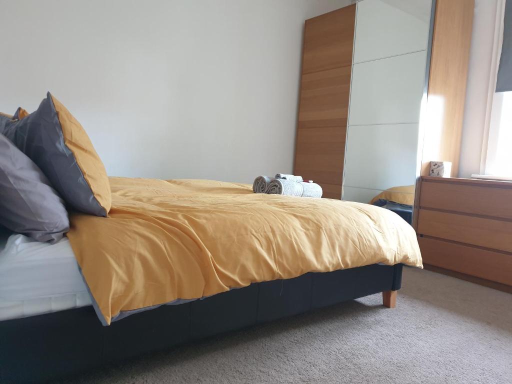 a bedroom with a bed with a yellow blanket and a dresser at Modern One Bed Apartment Greenwich in London