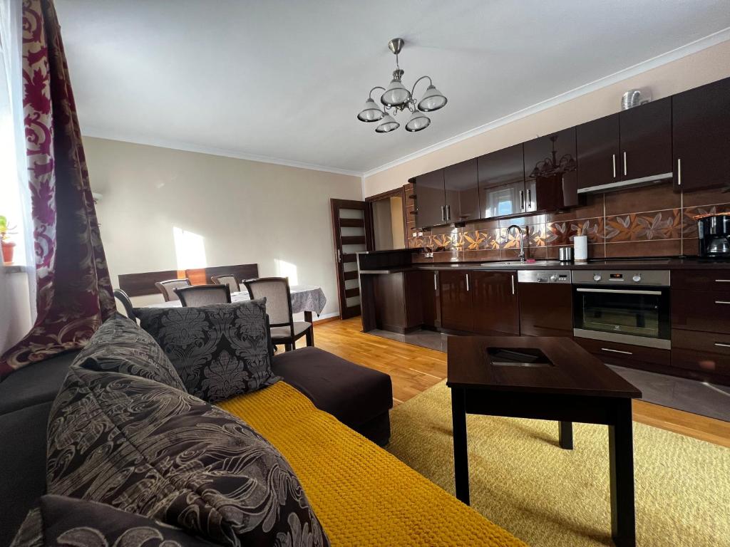 a living room with a couch and a kitchen at Apartament Słoneczny in Ustka