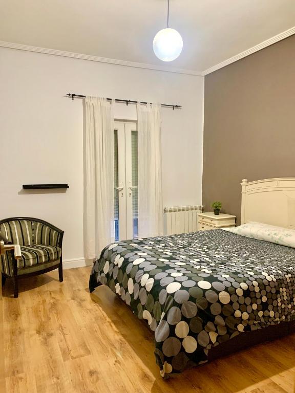 a bedroom with a bed and a chair at Antolín Yellow Door in Ponferrada