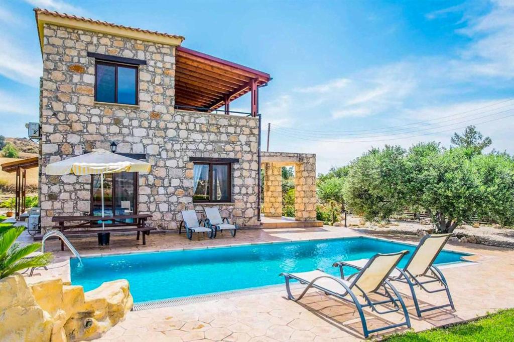 a villa with a swimming pool in front of a house at Villa Aphrodite Argaka in Argaka