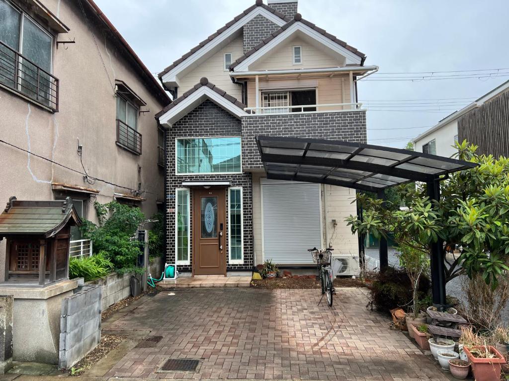 une maison avec un chien noir debout devant elle dans l'établissement Niji Homestay, à Osaka