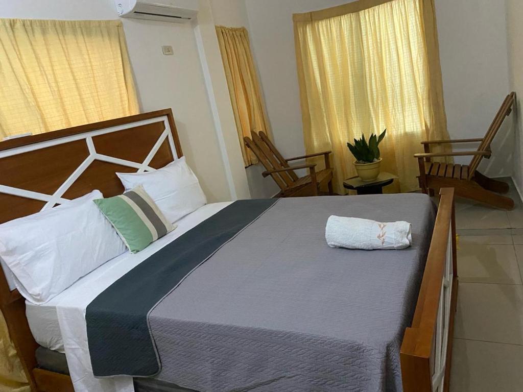 a large bed in a bedroom with two chairs at Apartamento JGB in Sosúa