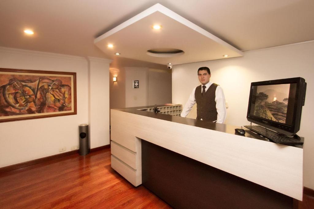 a man in a tie standing behind a counter at Hotel Torre del Bosque Pasto in Pasto