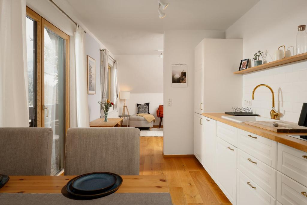 cocina con armarios blancos y sala de estar. en Haus Grundlsee en Grundlsee