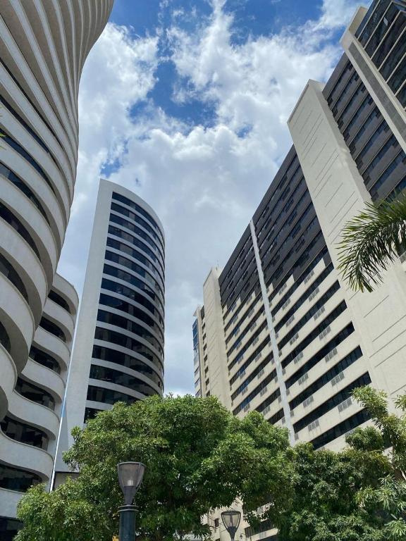 three tall buildings in a city with a palm tree at Puerto Santa Ana, Torres Bellini, 2 dormitorios, Parqueo in Guayaquil
