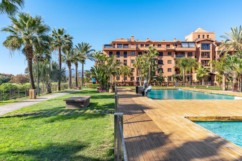a resort with a pool and palm trees and a building at Apartamento Dos Mares in Motril