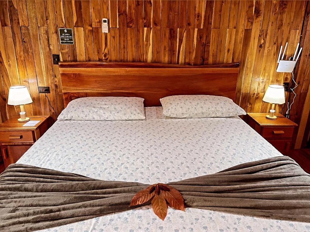 a bedroom with two beds with wooden walls and two lamps at Cacahua Paradise Lodge, Río Celeste in Rio Celeste