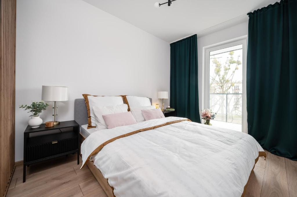 a bedroom with a large bed and a window at Manufaktura Residence - Apartamenty Prestiż z Garażem Podziemnym i Dwoma Łazienkami in Łódź