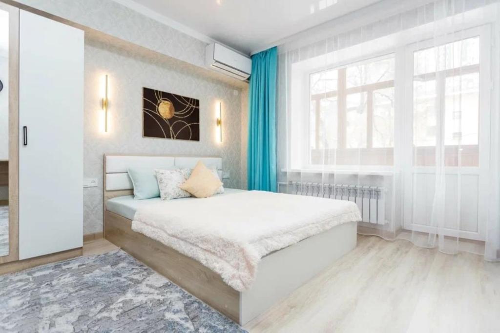 een slaapkamer met een bed en een raam bij Шикарная квартира в Золотом квадрате in Alma-Ata