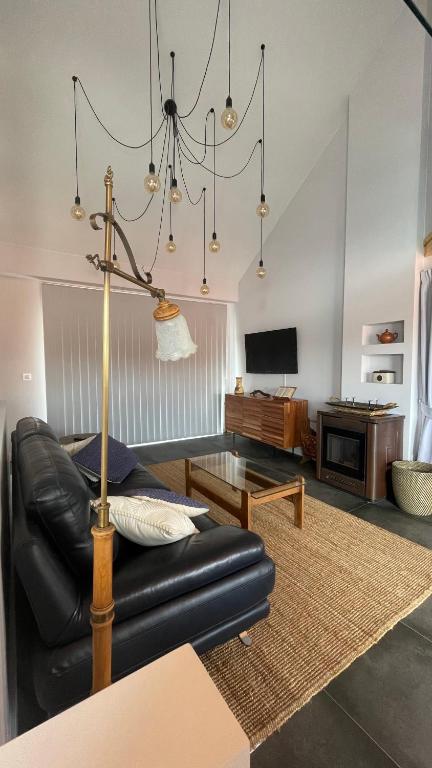 a living room with a black leather couch and a chandelier at Casa Pieiteiro in Corcubión