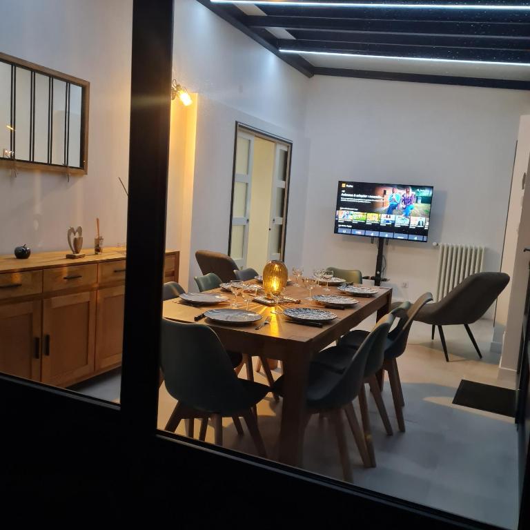 une salle à manger avec une table, des chaises et une télévision dans l'établissement Au rayon du soleil, à Roye