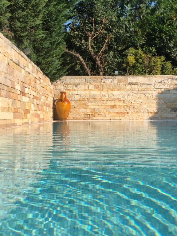 Villa Golf Club PRIVATE SWIMMING POOL في كاساماسيما: وجود مزهرية للجلوس بجانب جدار من الطوب بجانب مسبح