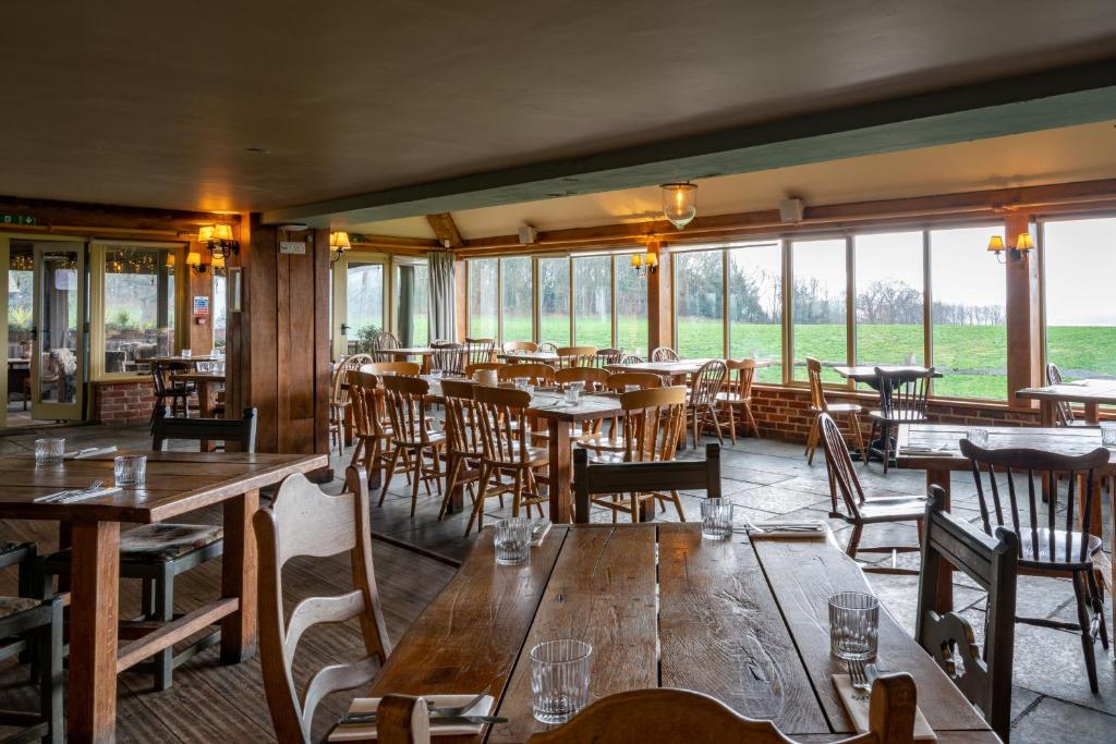 un restaurante con mesas y sillas de madera y ventanas en The Welldiggers Arms, en Petworth