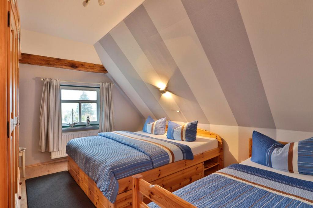 two beds in a attic room with a window at Reetdachhaus am Haff in Pepelow