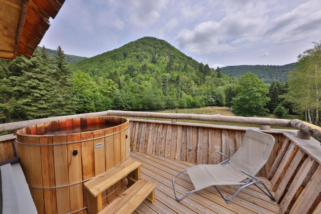 une terrasse en bois avec une chaise et un bain à remous dans l'établissement ESCALE CAB'ÂNE, à Mittlach