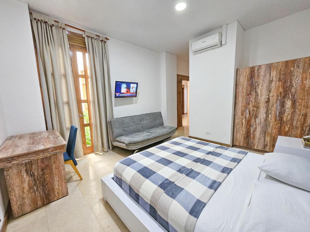 1 dormitorio con cama, sofá y TV en La Mercedes Boutique Hostal By MH en Cali