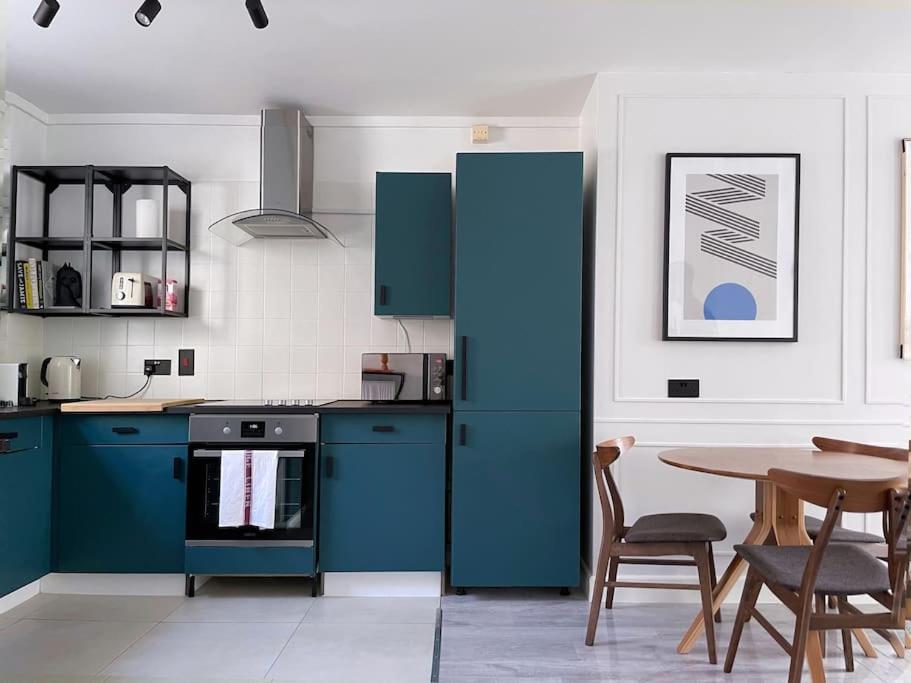 eine Küche mit einem blauen Kühlschrank und einem Tisch in der Unterkunft Contemporary central flat in Clerkenwell Green in London