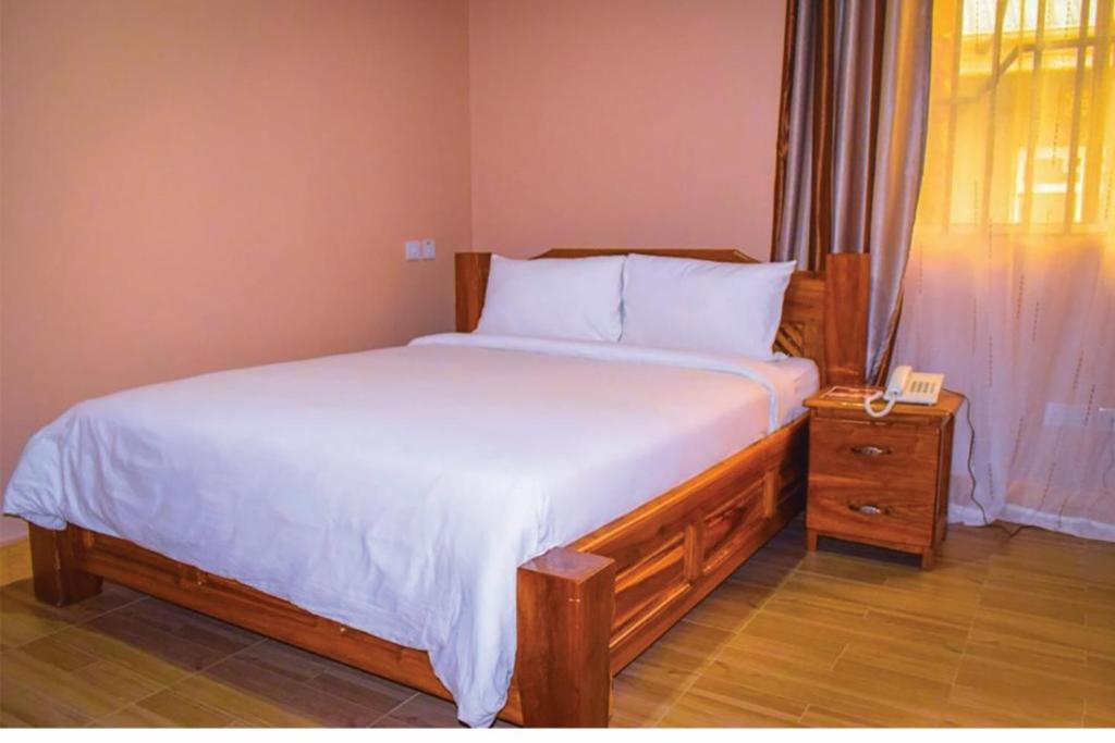 um quarto com uma cama e um telefone numa mesa de cabeceira em Briston Hotel - Mugumu em Mugumu