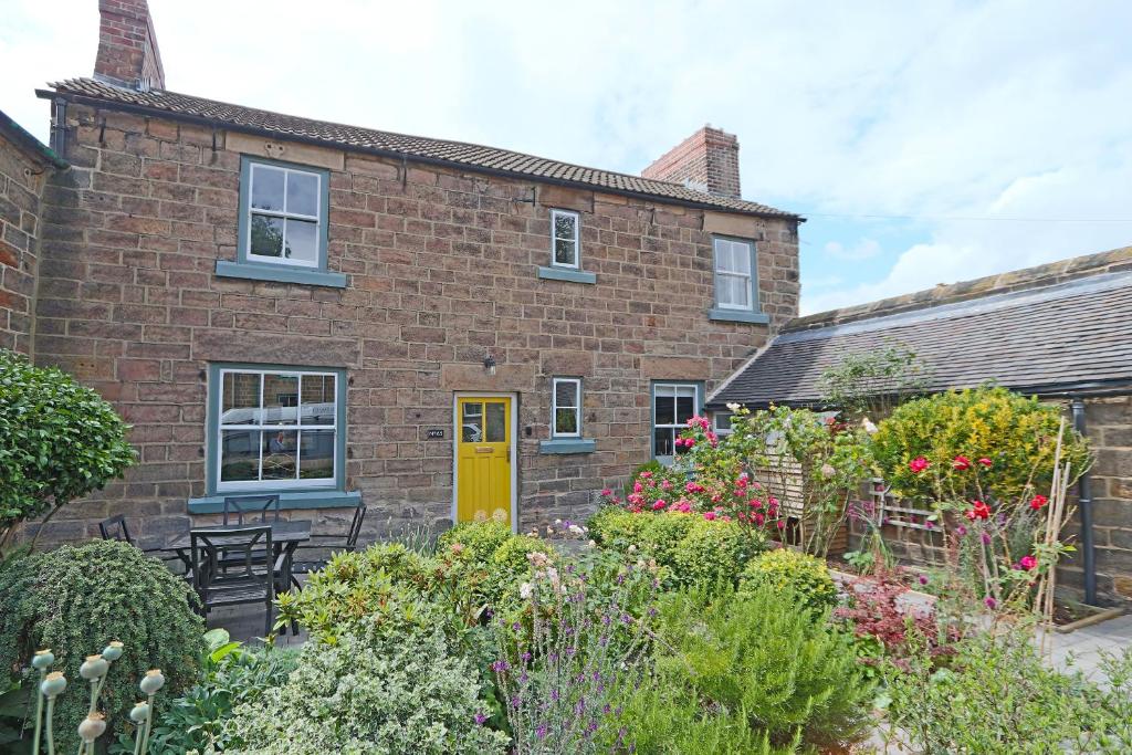 una casa in mattoni con una porta gialla e un giardino di Beautiful Character Cottage a Milford