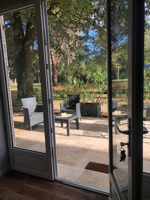 an open door to a patio with chairs and tables at GITE LA BASTIDE DE NEGRA in Montesquieu-Lauragais