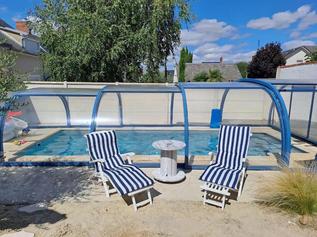 2 sillas y una mesa junto a la piscina en Chambre bleue avec accès plage en Bourges