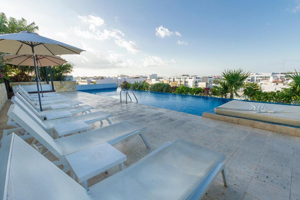 un gruppo di sedie e un ombrellone accanto alla piscina di Apartment in Excellent Location a Playa del Carmen