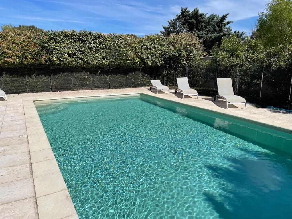 einen Pool mit zwei Stühlen und einem Pool mit Wasser in der Unterkunft La maison d'Amélie, Villa climatisée piscine privée 4 Chambres, 3 sdb in Mazan