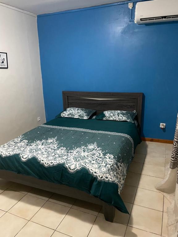 Le Zonappart في Pamandzi: سرير في غرفة ذات جدار ازرق