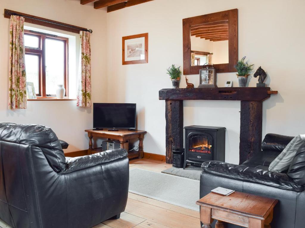 a living room with a fireplace and leather furniture at The Old Stable - Meadowbrook Farm in Thame