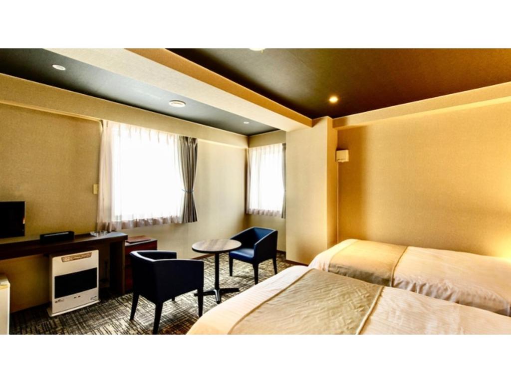 Hotel Three M - Vacation STAY 93395v في كوتشان: غرفة فندقية بسريرين ومكتب