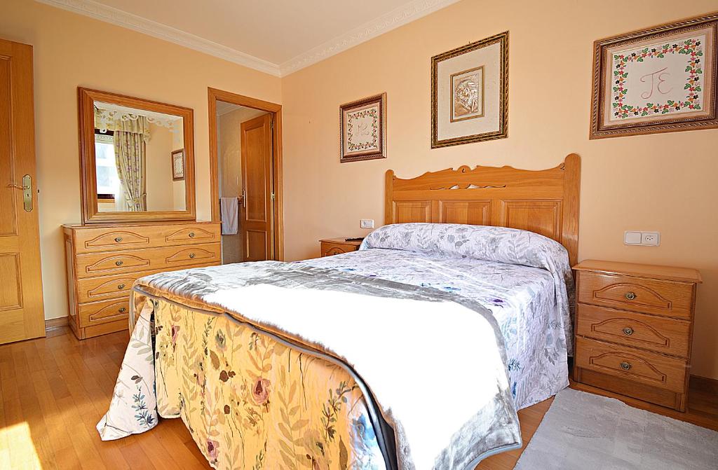 - une chambre avec un grand lit et un mobilier en bois dans l'établissement Apartamento As Carolinas, à Vilagarcía de Arousa