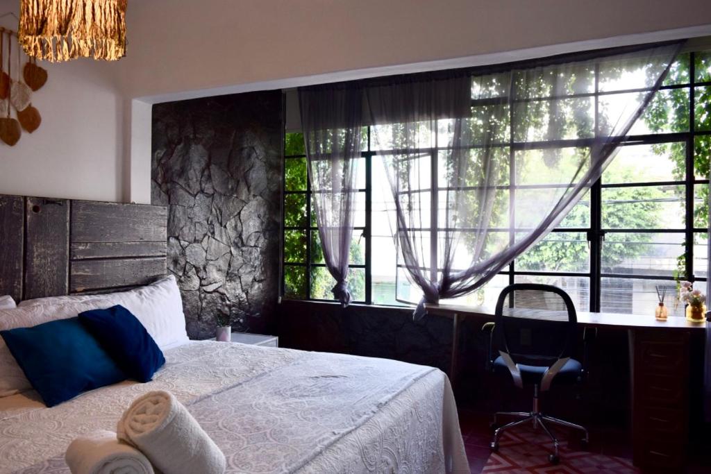 a bedroom with a bed and a desk and windows at Casa Miranda Balbuena in Guadalajara