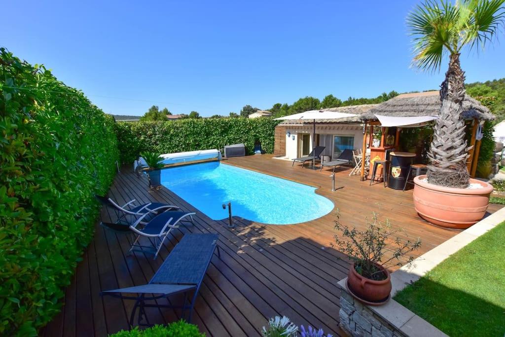 une terrasse en bois avec une piscine et une maison dans l'établissement Villa le 62 Cazan, à Vernègues