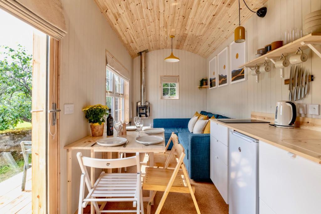 a kitchen and dining room with a table and chairs at Enchanting Tiny House with wood burner and hot tub in Cairngorms in Ballater