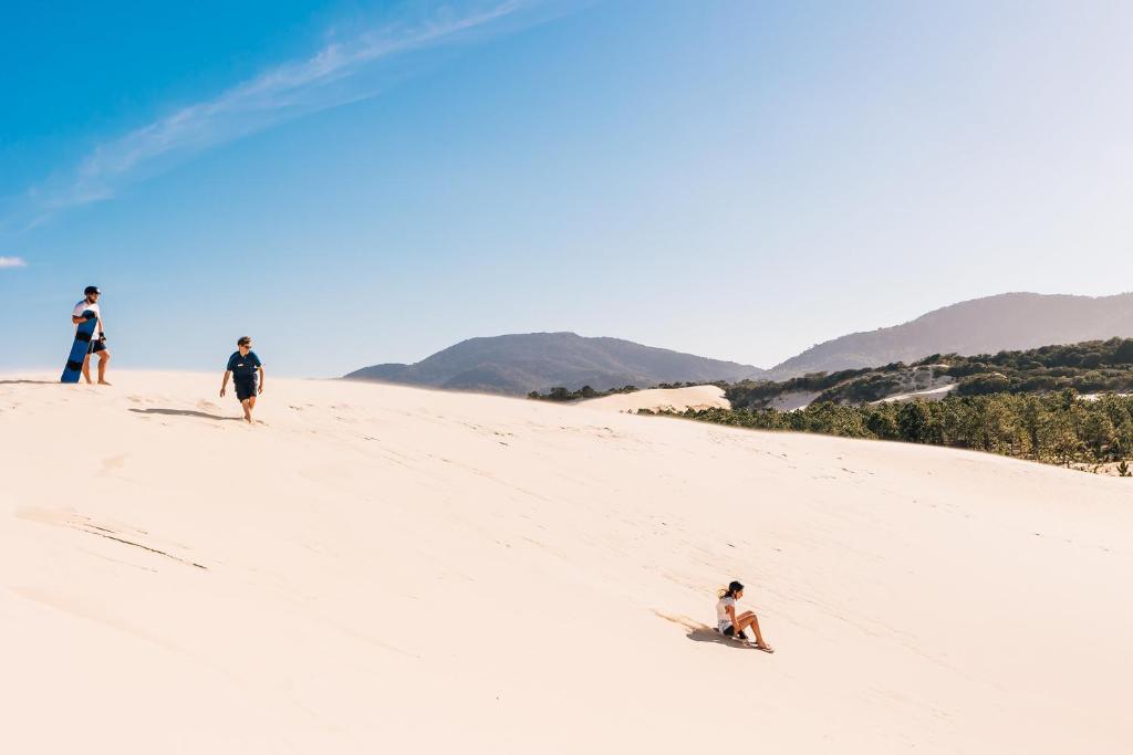 a group of people walking up a sand hill at Costao do Santinho Resort All Inclusive in Florianópolis