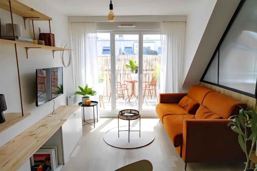a living room with an orange couch and a table at Appart - Élégant - Chic - Paris-Disneyland - RER A - Self-Check In - NETFLIX - WIFI Ultra Rapide in Noisy-le-Grand