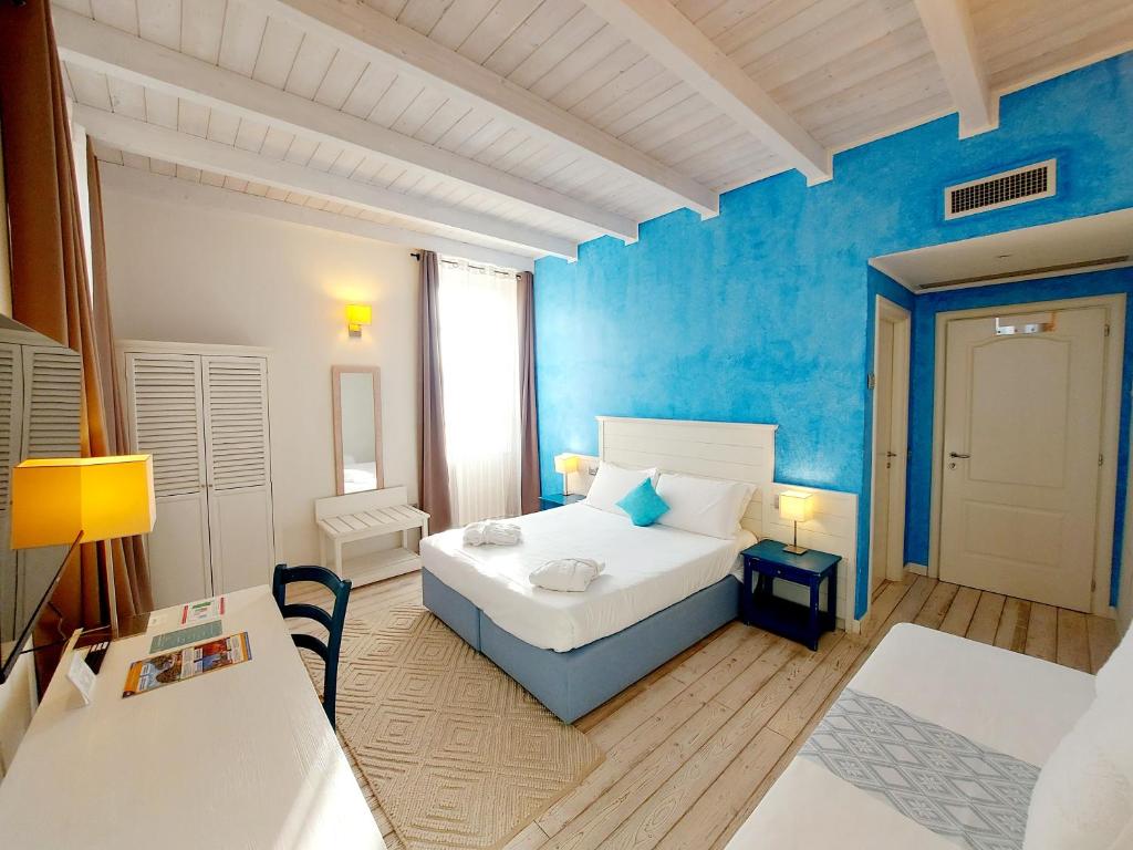 a bedroom with a white bed and a blue wall at Hotel La Villa Del Mare in Cagliari