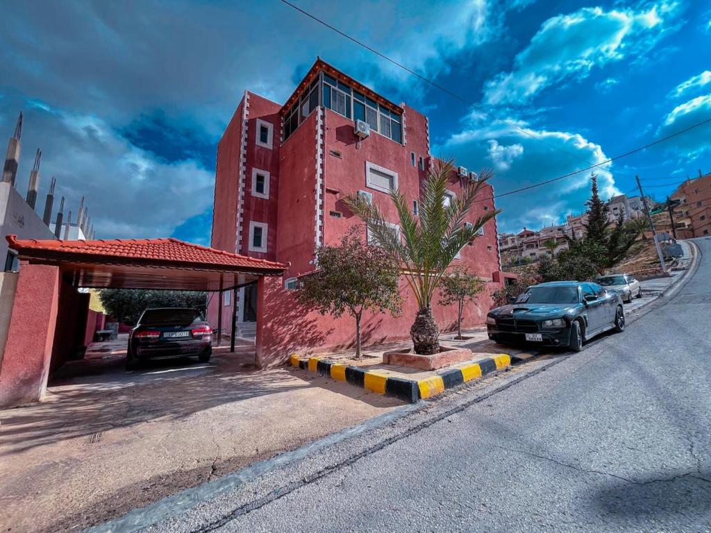 una calle con coches estacionados frente a un edificio rojo en Petra Caravan Guest House, en Wadi Musa