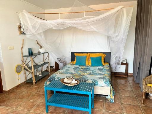 a bedroom with a blue bed with a canopy at Bungalow vue mer avec jardin in Sainte-Luce