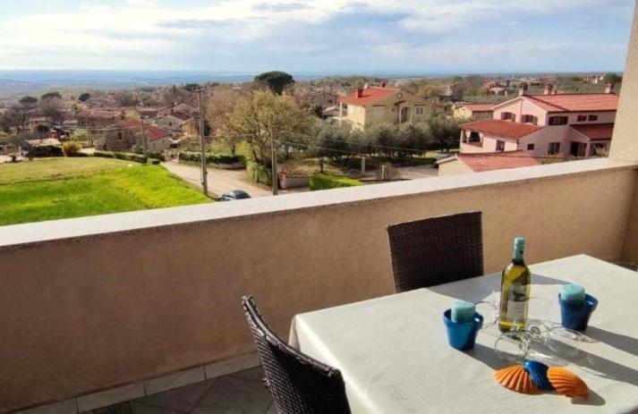een witte tafel met een fles wijn op een balkon bij Apartment Lorena in Kaštelir