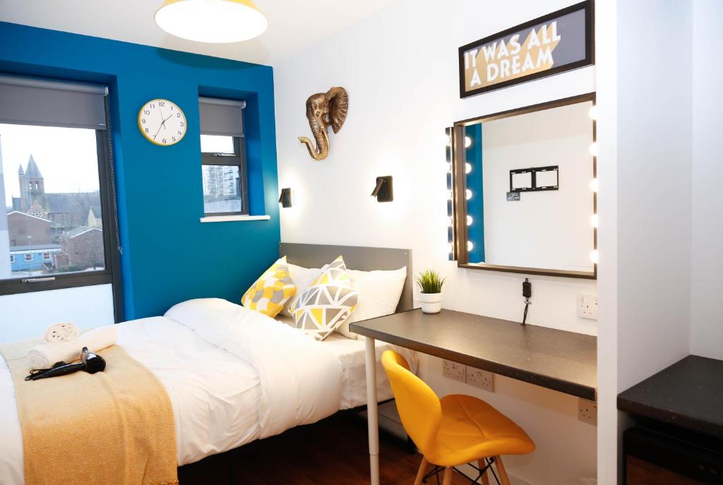1 dormitorio con una pared de acento azul, 1 cama y escritorio en London City Self Check-in Luxury Rooms en Londres