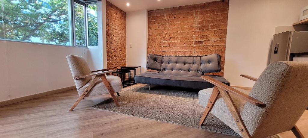 a living room with a couch and two chairs at Apartaestudios Margarita in Bogotá