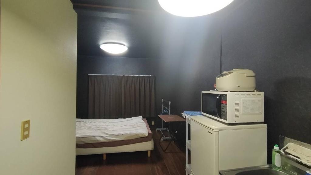 a room with a bed and a microwave on a refrigerator at Shirakkan - Vacation STAY 15831 in Hamura