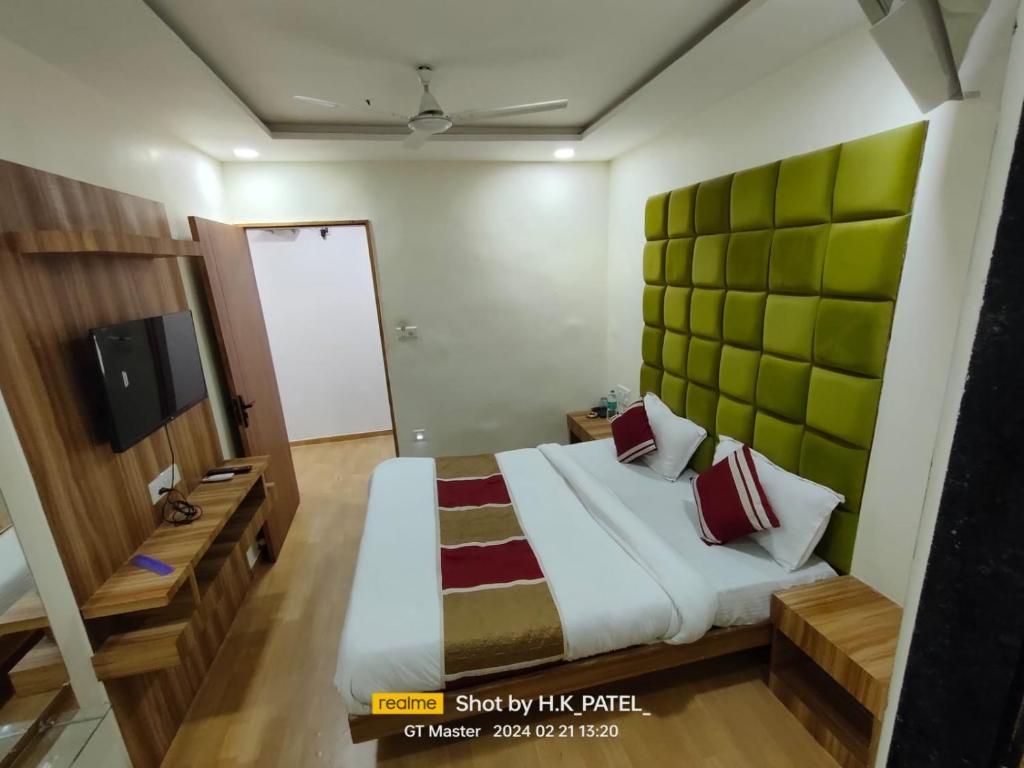 a bedroom with a large bed with a green headboard at Hotel Happy Stay in Ahmedabad