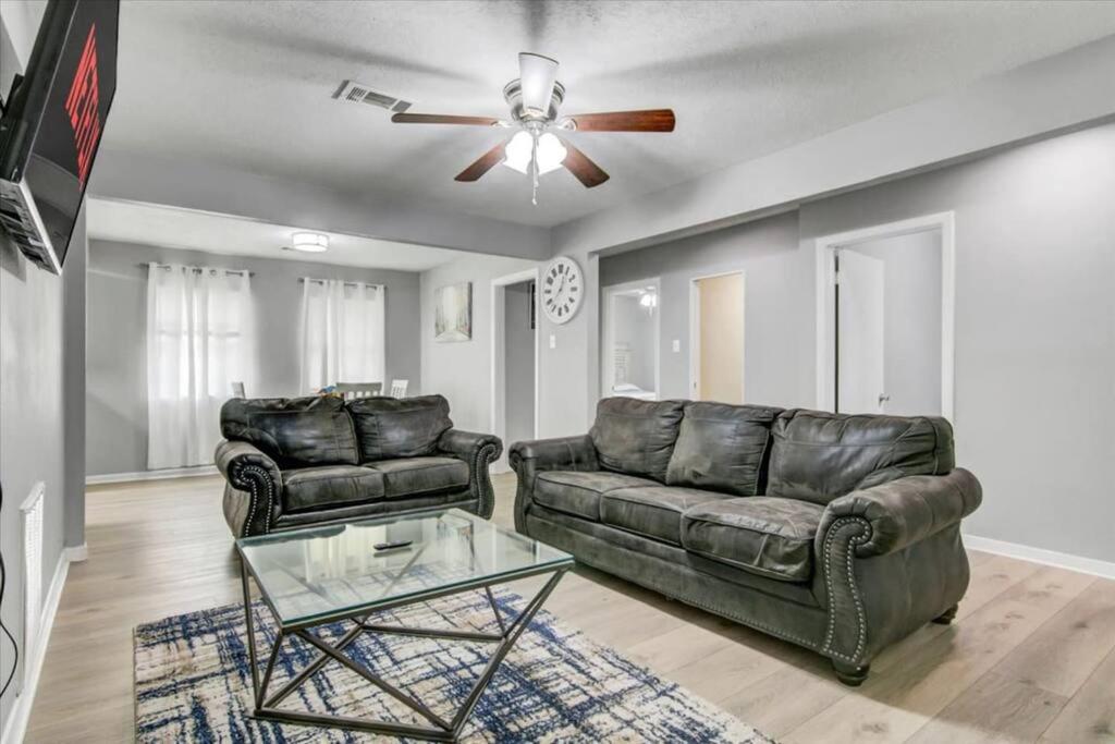 a living room with two leather couches and a ceiling fan at Comfy 3 bedroom home w/ fenced yard in Bridge City