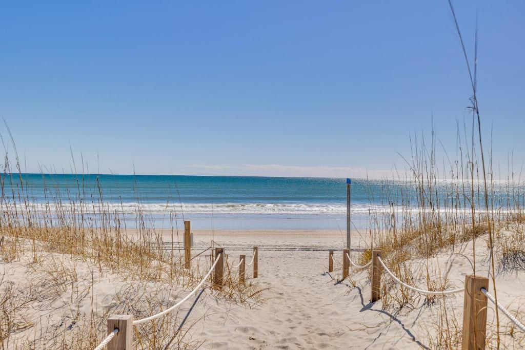 a sandy beach with a fence and the ocean at Ocean-View Apt in Emerald Isle - Walk to Beaches! in Emerald Isle