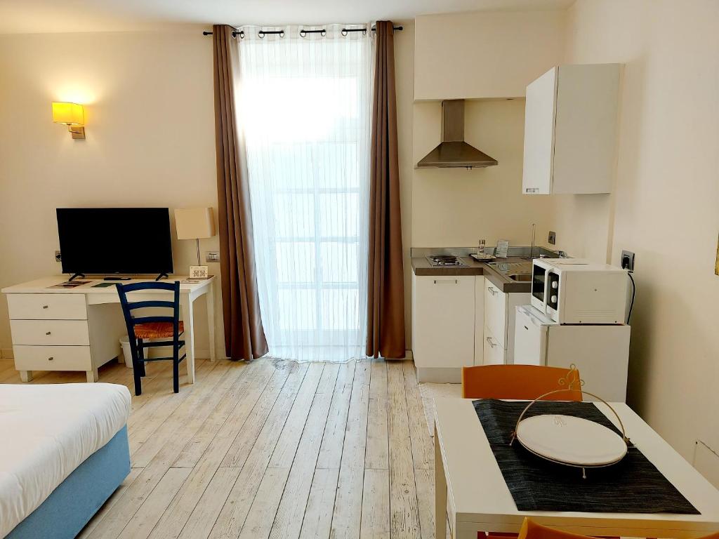 a room with a bed and a desk and a kitchen at Hotel La Villa Del Mare in Cagliari